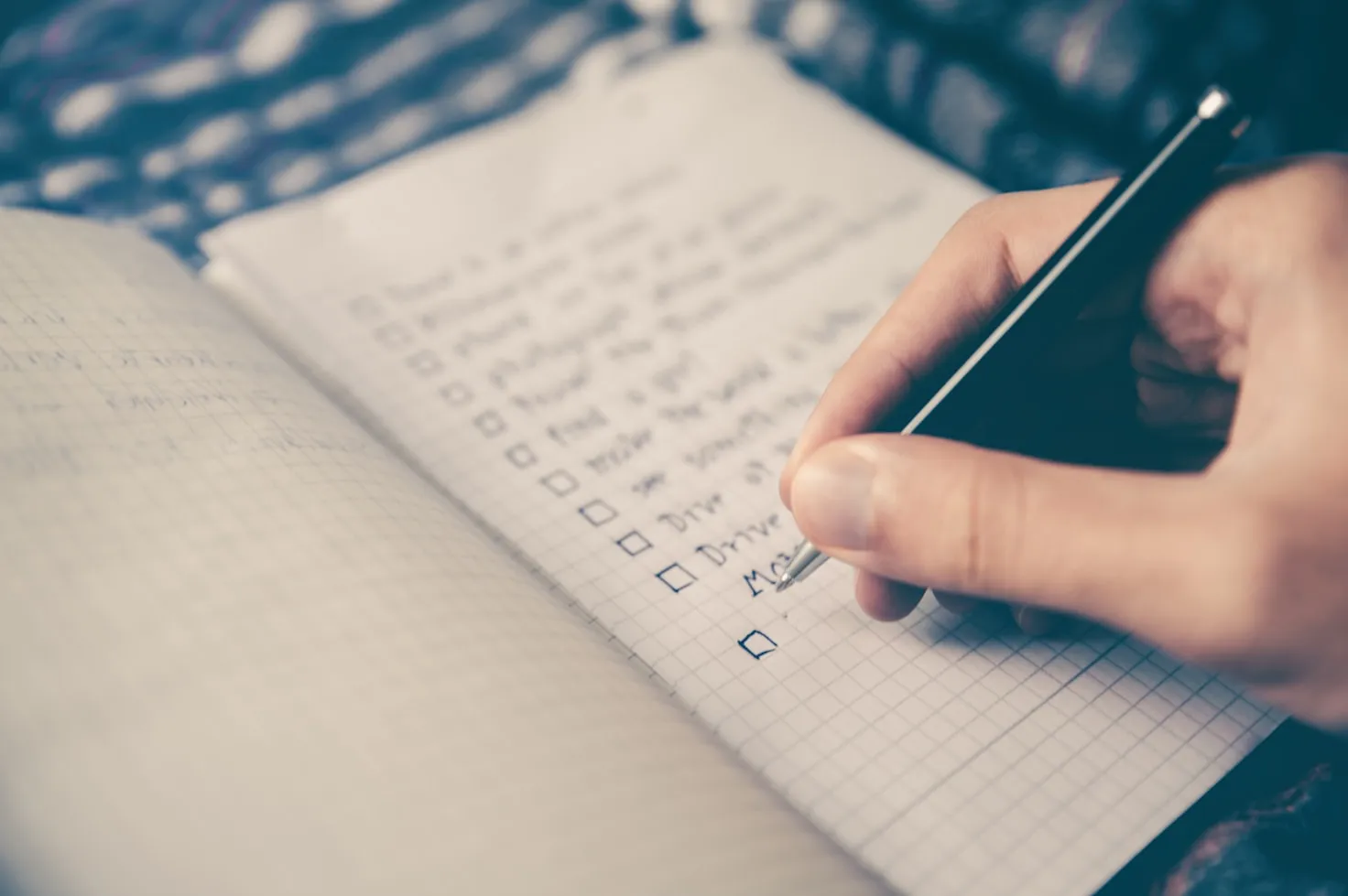 A person at a clean desk making a to-do list, symbolizing organization and productivity.